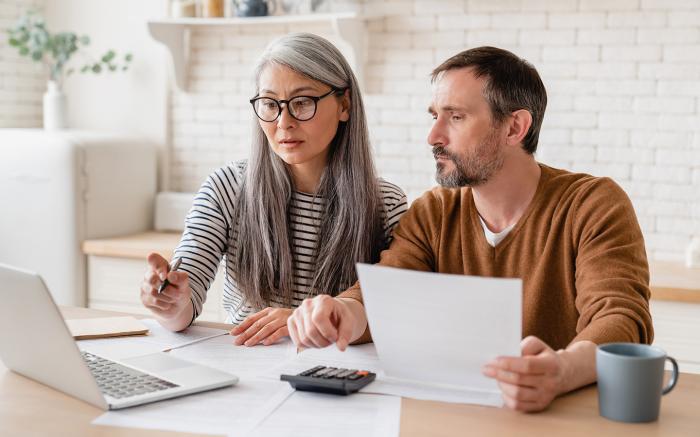 middle aged couple looking over documents on laptop