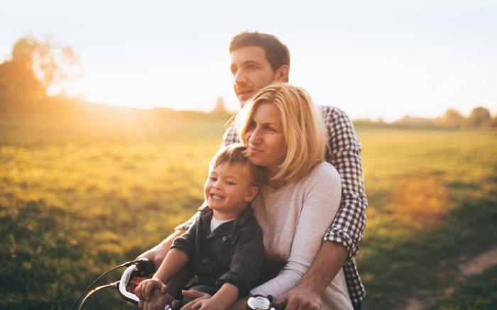 husband wife and child riding a bike on a path