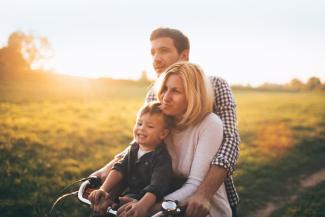 husband wife and child riding a bike on a path