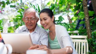 father and daughter in garden looking at a computer