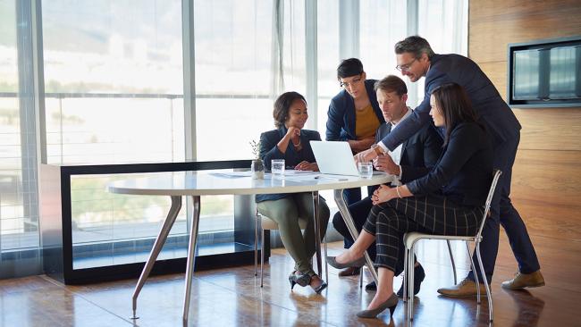 5 engineers looking at a computer in a boardroom