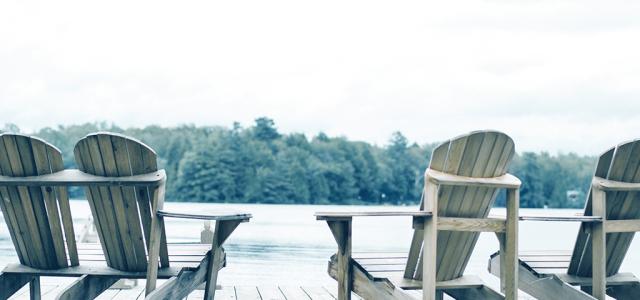 four wood adirondack chairs on a wood dock